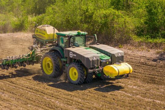 A tractor sowing seeds in a rural field on a sunny day in Prospect, NC.