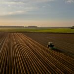 a tractor plowing a field at sunset